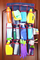 Household chemicals in holder hanging on wooden door background